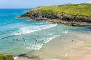 Poldhu Cove beach with surfers learning to surf, Cornwall